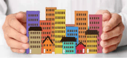 Toy buildings between a man's hands.